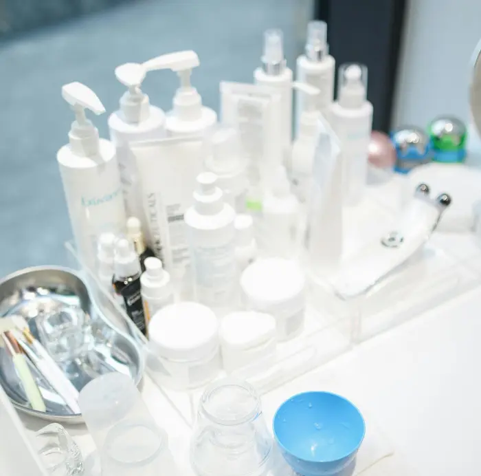 A neatly organized vanity with various skincare products, including bottles, jars, and a facial massage device, all arranged on a white tray.