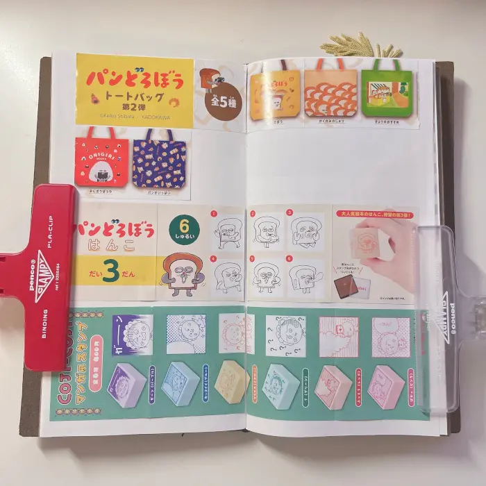 Assorted gashapon capsule toy leaflets organized in a Traveler's notebook