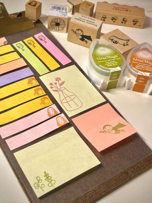 Assorted sticky notes with pastel colors and small illustrations, surrounded by washi tapes and stamps.