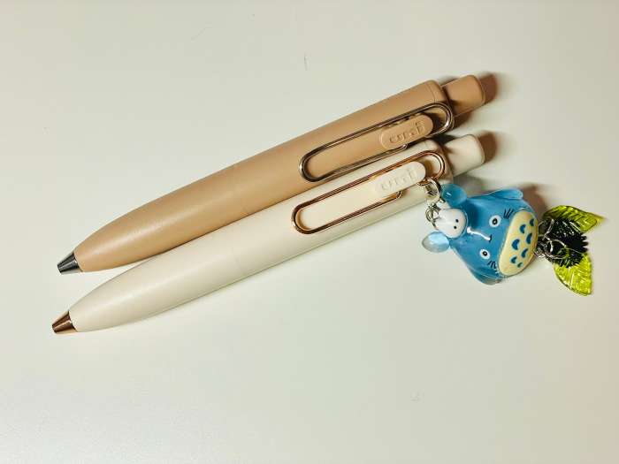 Uni-ball One P in mocha and white with metal clips and a totoro charm decoration