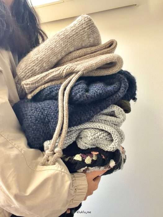 Hand holding a bundle of knitted garments and accessories