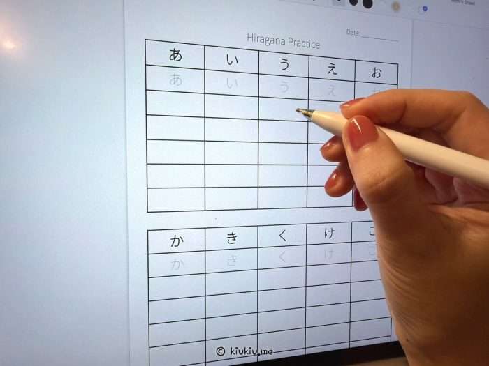 Practicing hiragana and katakana on a Japanese writing worksheet with a pen, beginner Japanese study routine