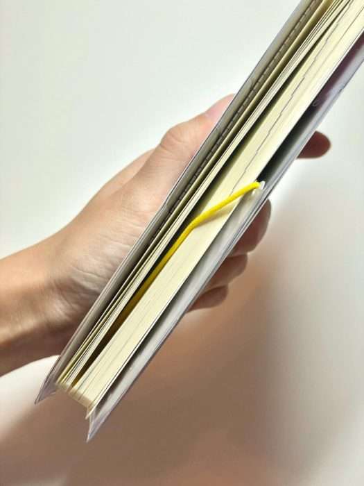 Hobonichi Weeks held in hand with yellow elastic page keeper inserted between pages