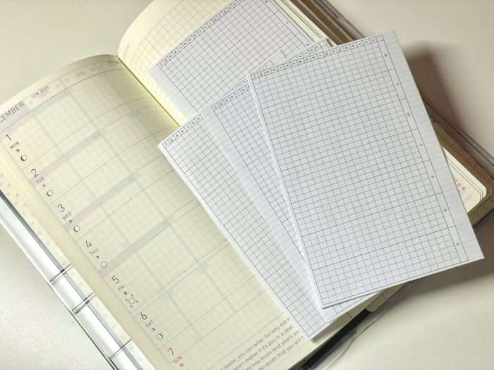 Cut-out time tracker sheets placed on top of a Hobonichi Weeks weekly planner page