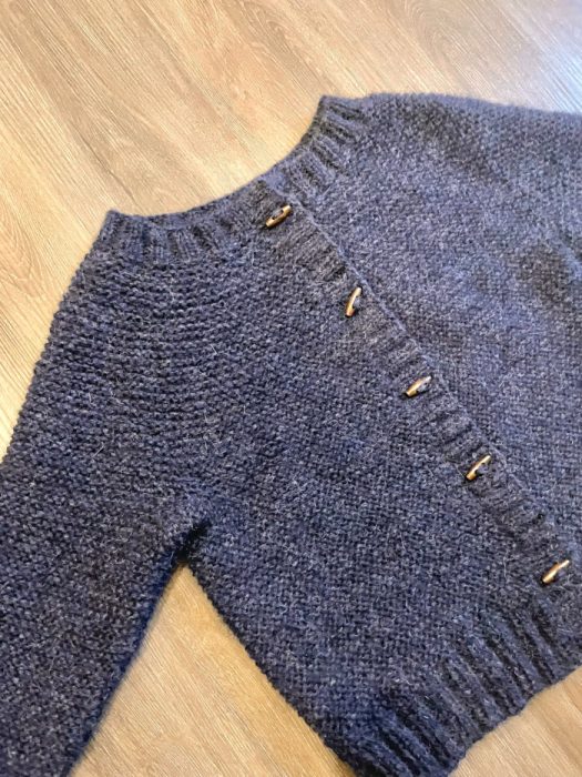 finished navy Kiki cardigan laid flat on wooden floor with wooden toggle buttons