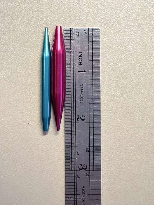 Short knitting needle tips placed next to a ruler showing short needle length