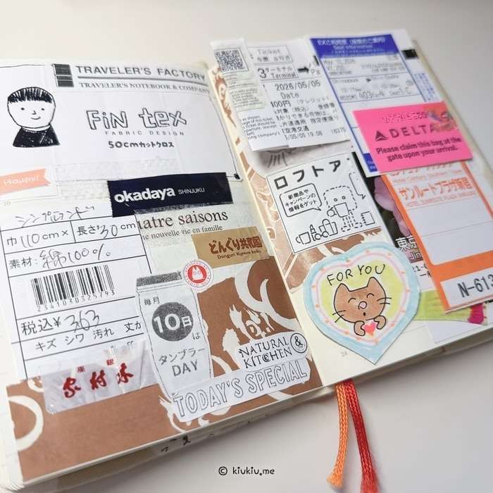 An open Japan travel journal with a collage of tickets, receipts, stickers, fabric labels, and small paper scraps from a Tokyo trip.